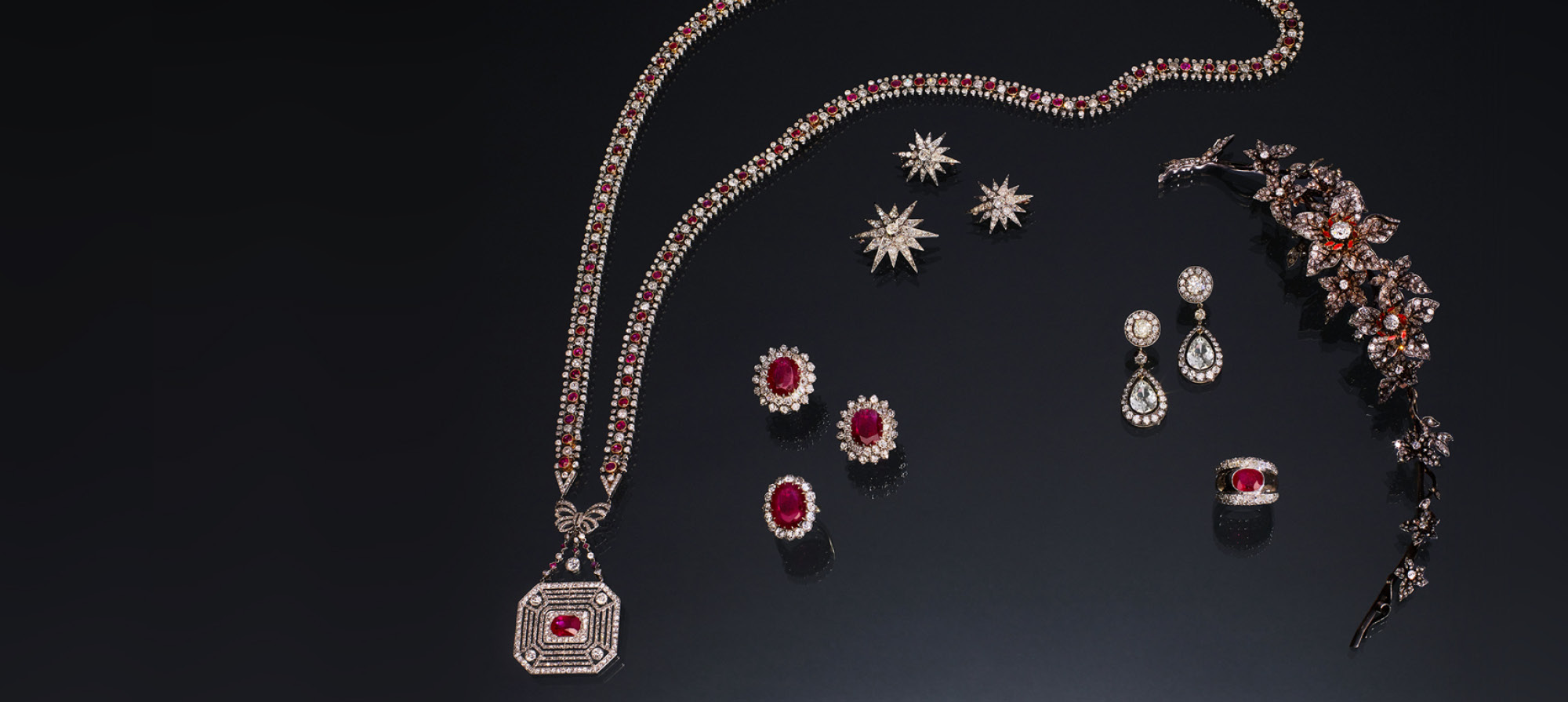 Collection of ruby jewelry items necklace, earrings, broach and rings set on black background